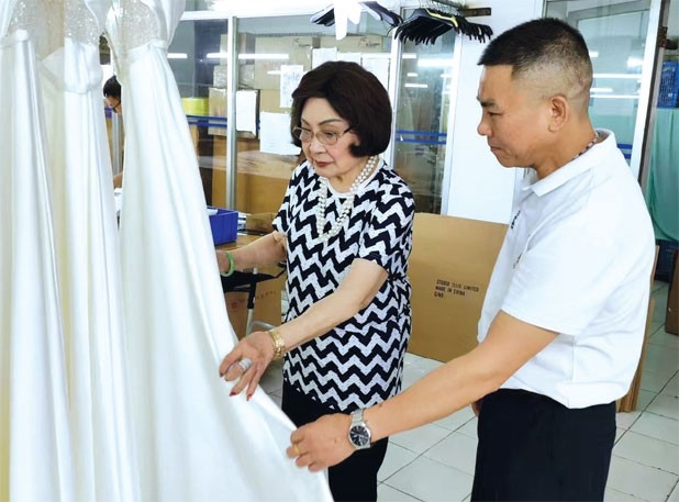 Mok discusses the design of an evening gown with an employee. Photos Provided to China Daily